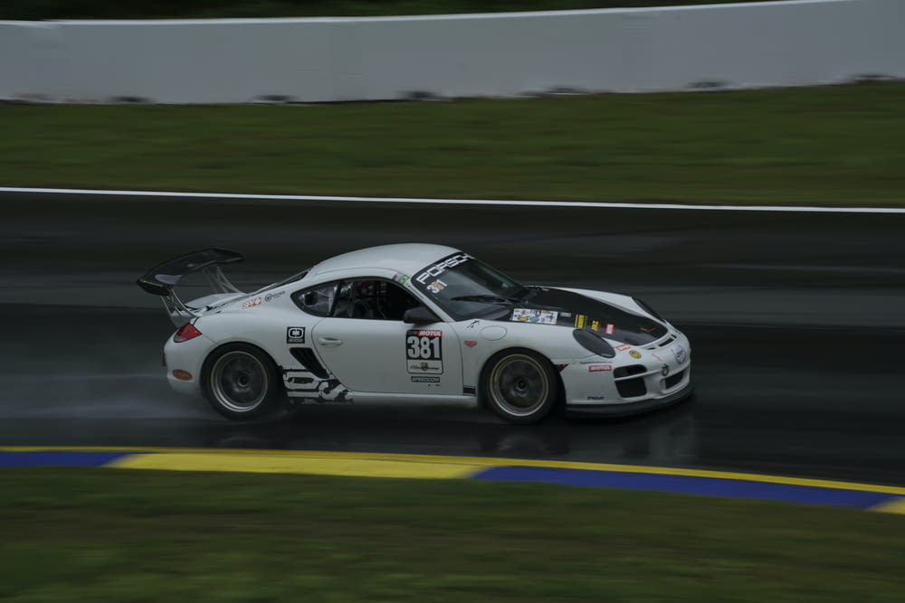 a white sports car driving on a wet track