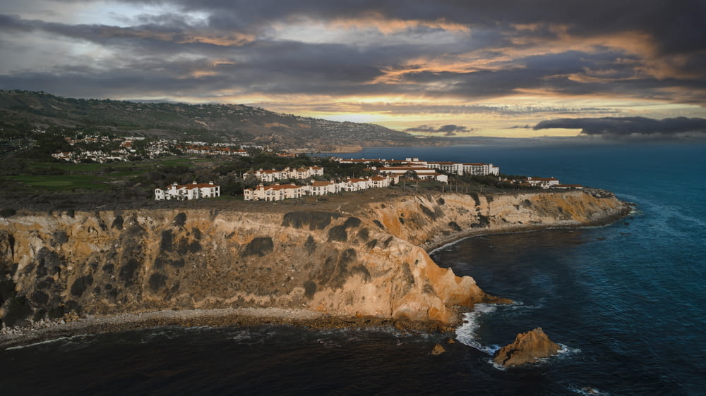 a scenic view of a town on a cliff near the ocean