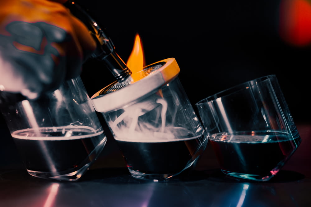 a person pouring a drink into three glasses