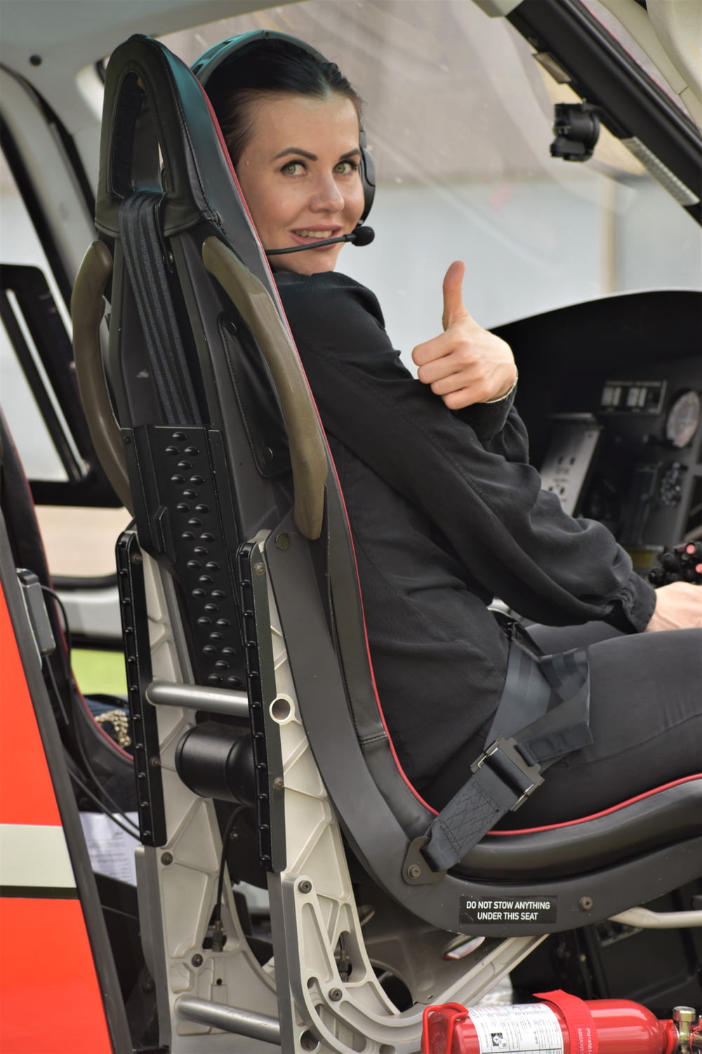 a woman sitting in the cockpit of a helicopter giving a thumbs up