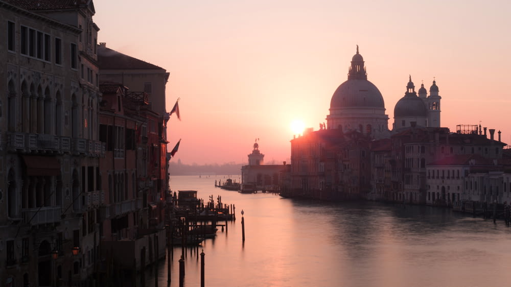 the sun is setting over the water in venice