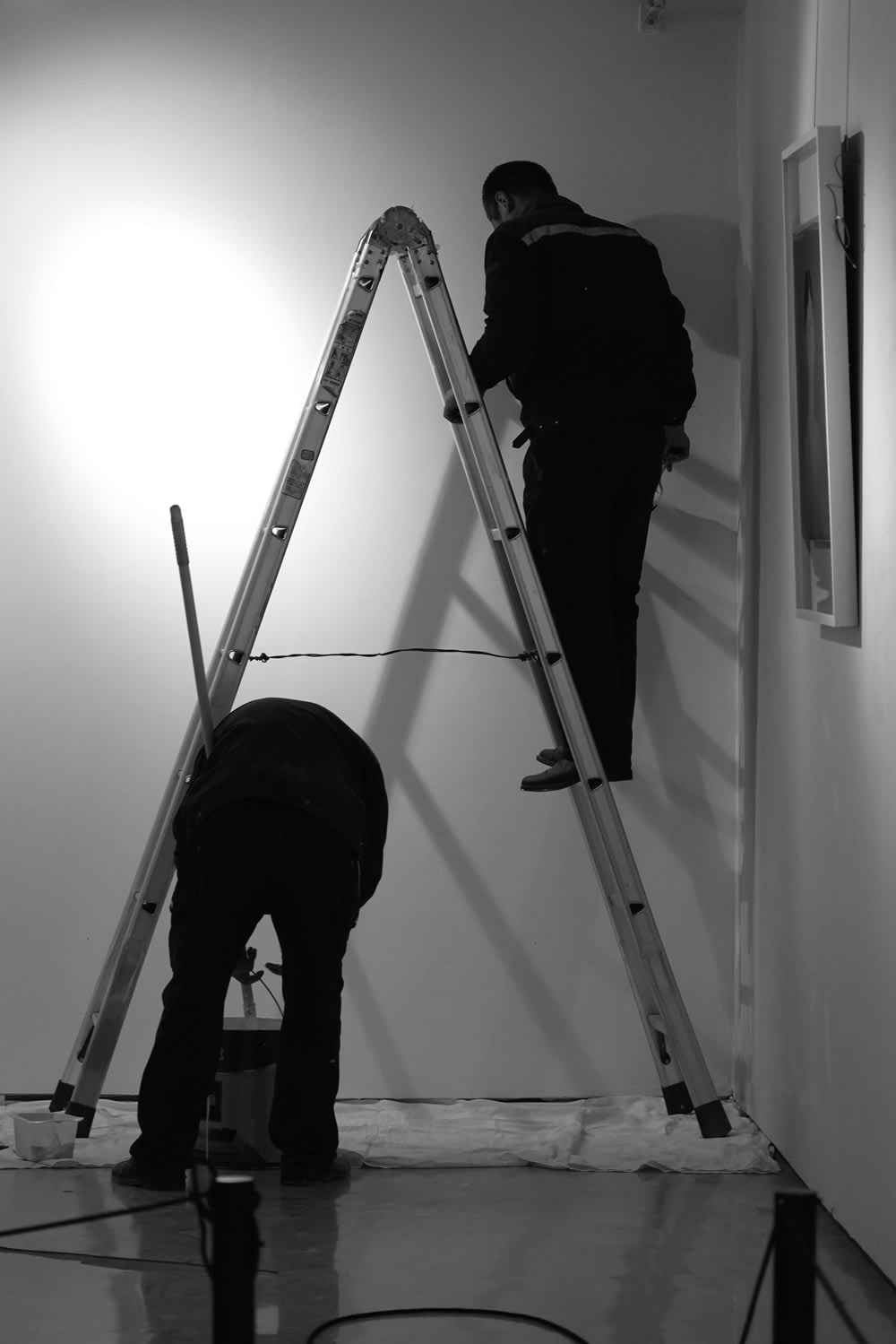 two men are painting a wall with ladders