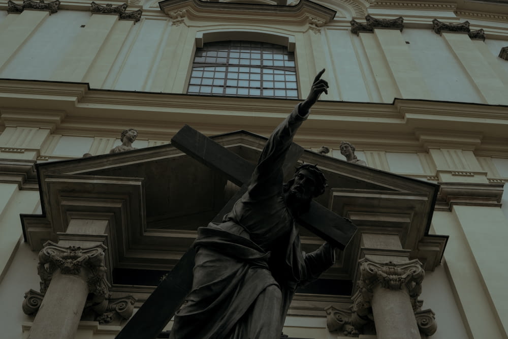 a statue of a person holding a cross in front of a building