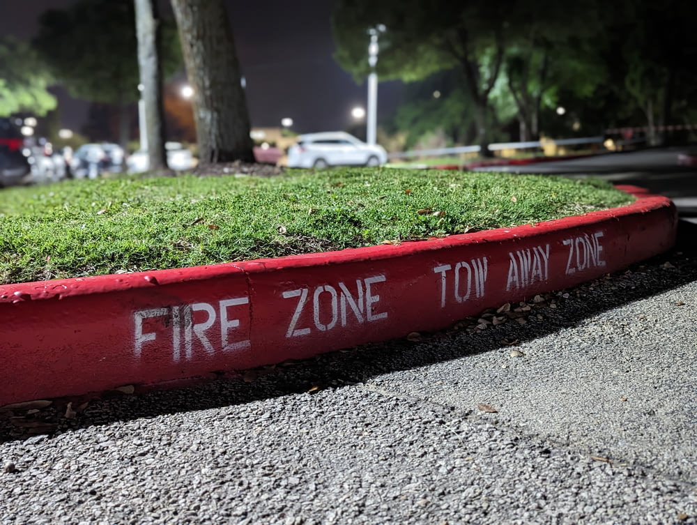a red fire zone sign sitting on the side of a road