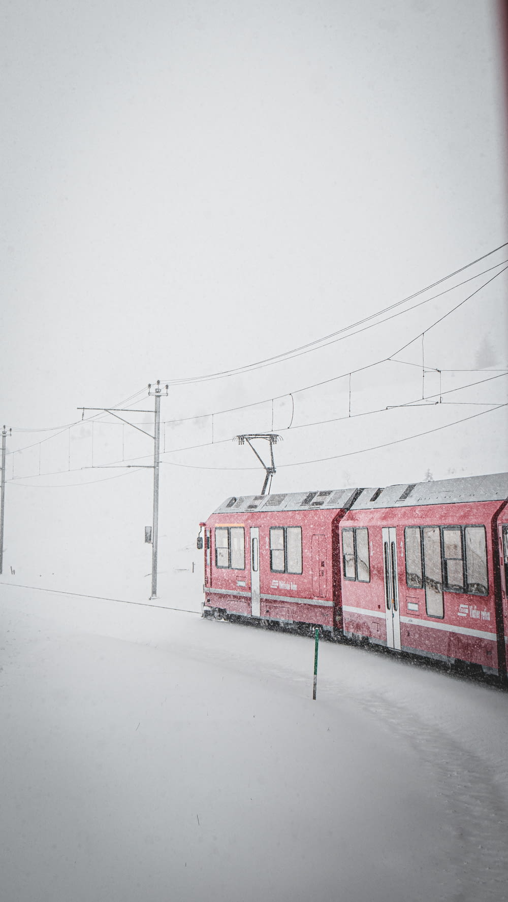 a red train traveling down train tracks covered in snow