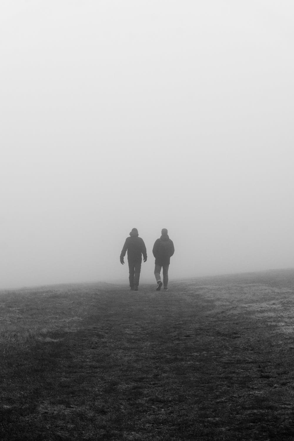 two people walking in the fog on a hill