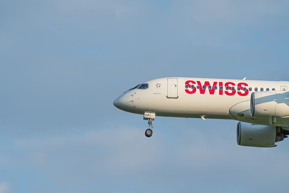 a white and red swiss airplane flying in the sky
