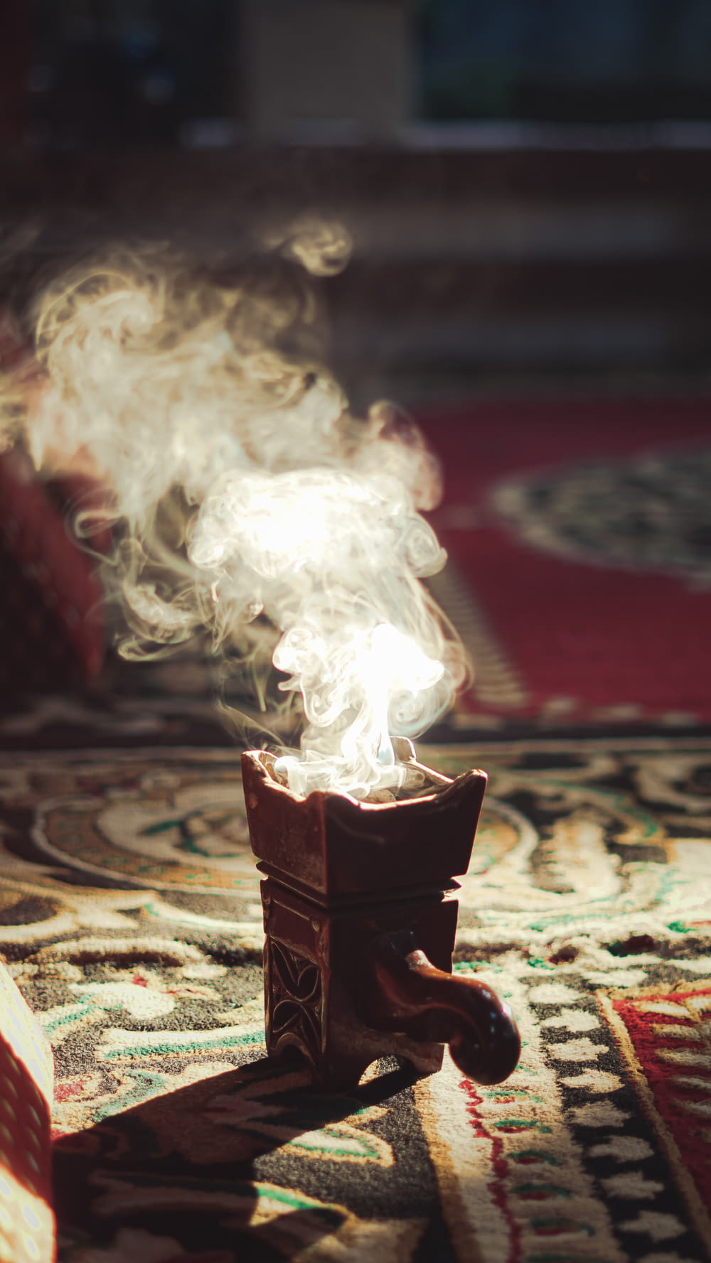 a small incense burner on a rug with smoke coming out of it