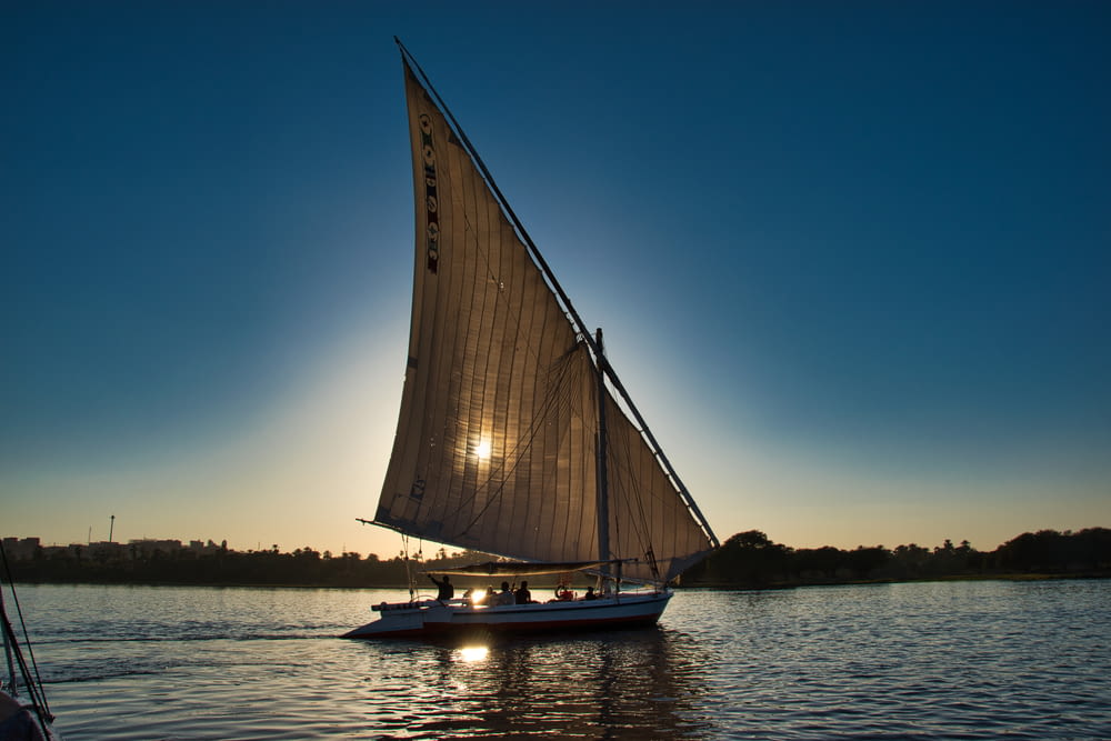 a sailboat sailing on the water at sunset