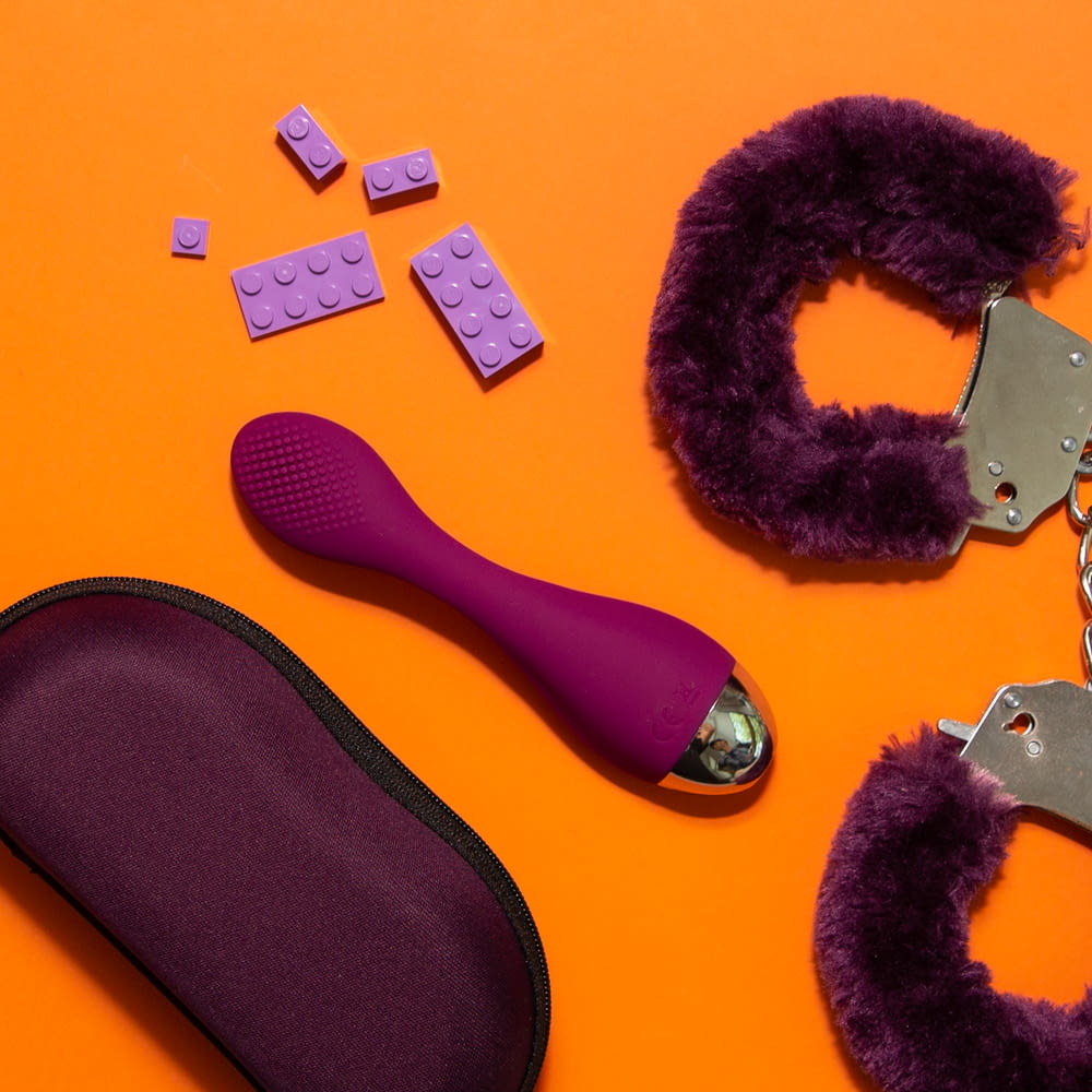 a pair of scissors, a purple case, and a purple object on an orange