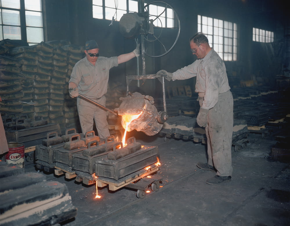 two men in a factory working on a piece of metal