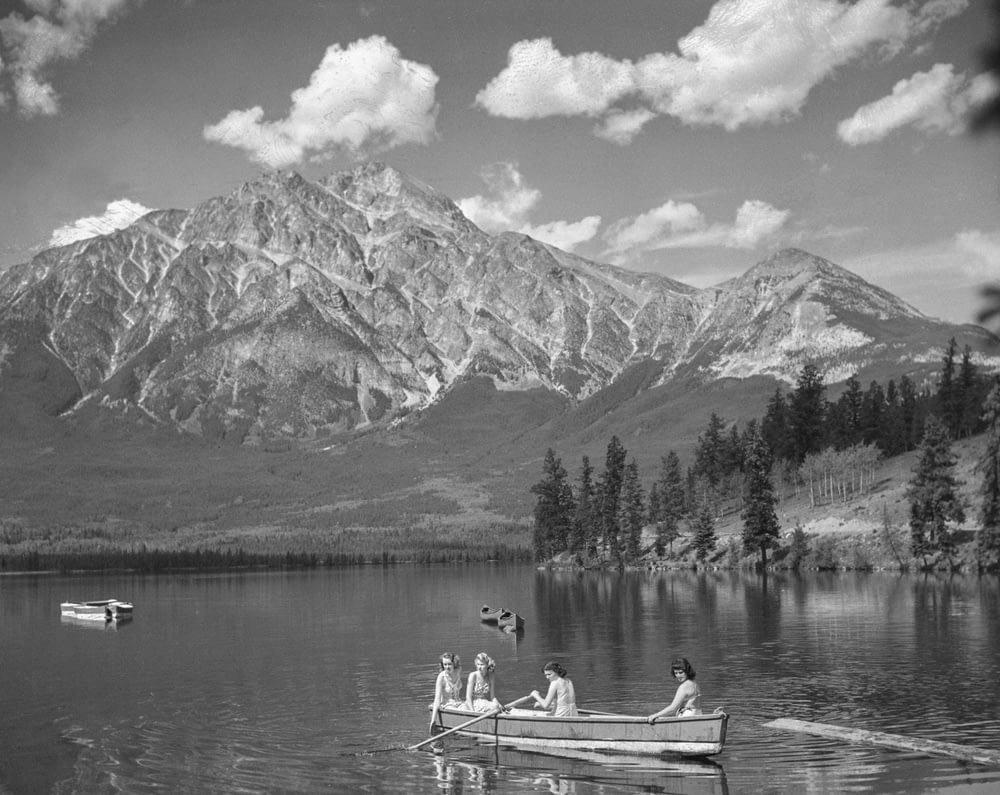 a black and white photo of people in a boat on a lake