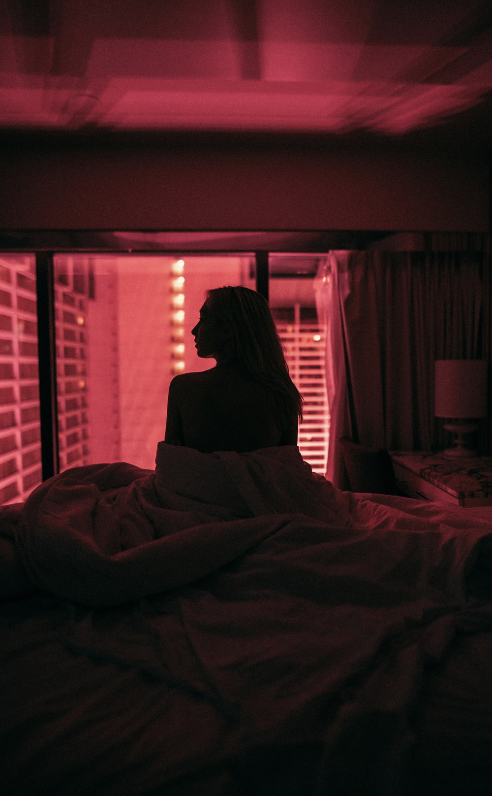 a woman sitting on a bed in a dark room