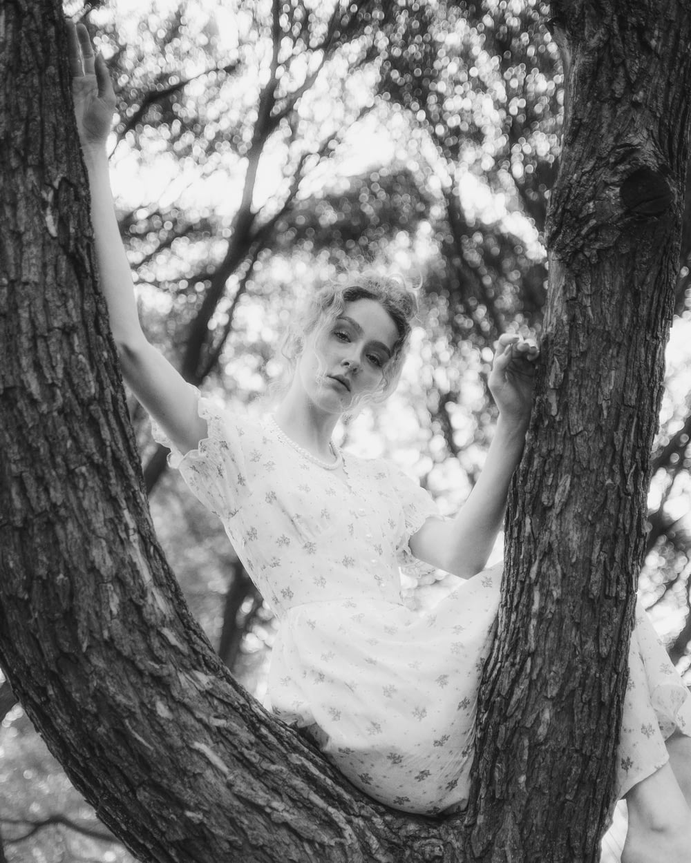 a woman in a white dress sitting in a tree