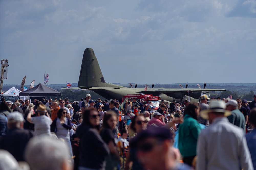 a crowd of people standing around a military plane