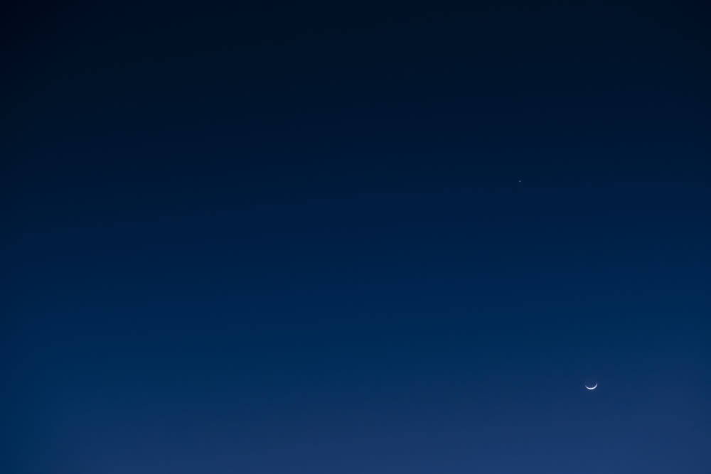 a plane flying in the sky with a moon in the background