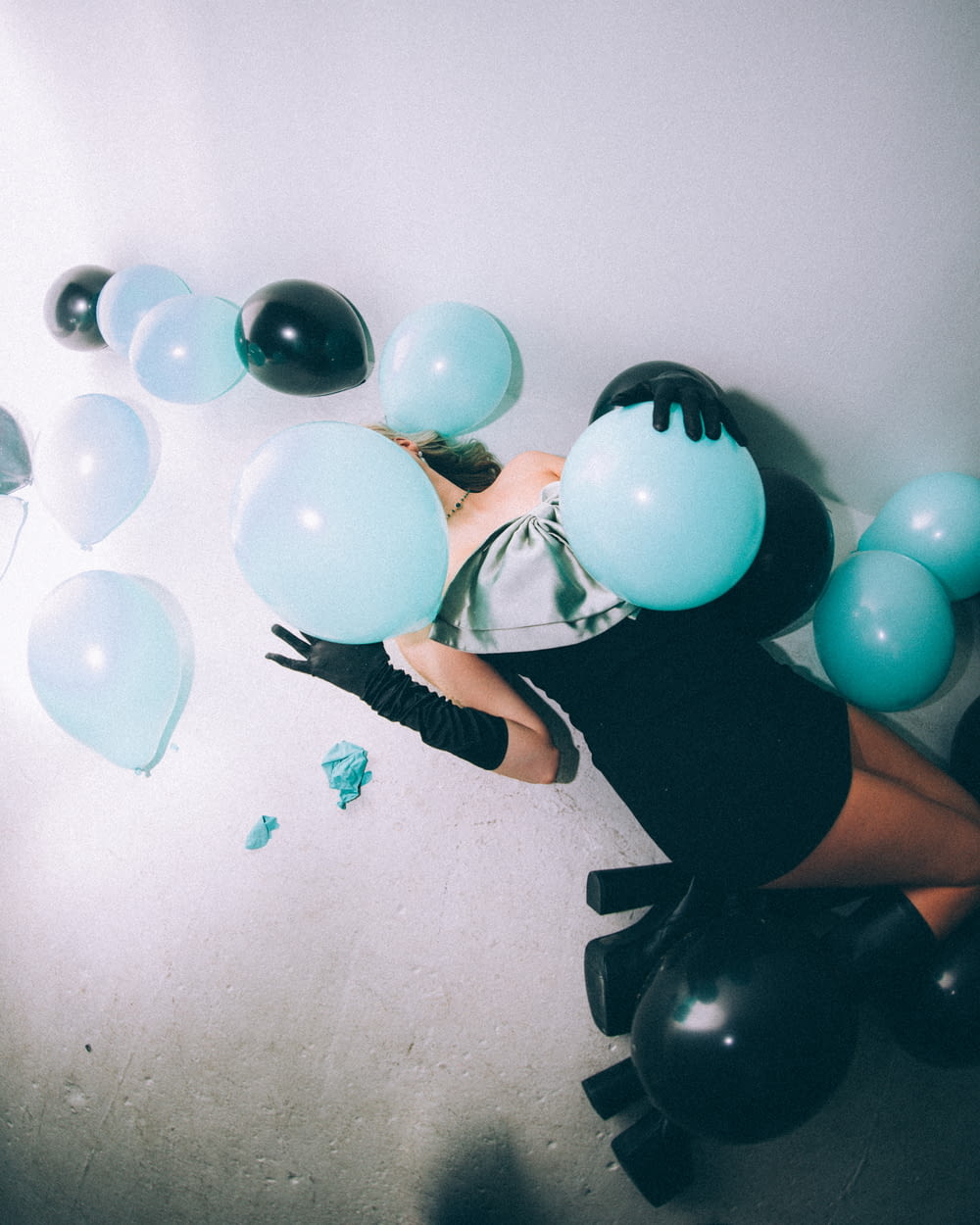 a woman in a black dress is surrounded by balloons