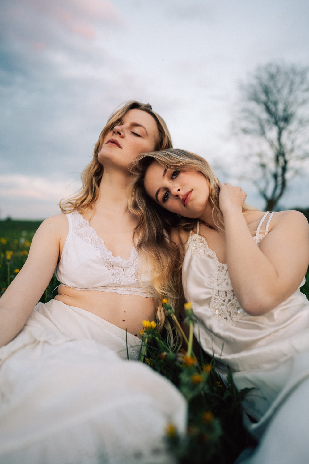 two women are sitting in a field of flowers