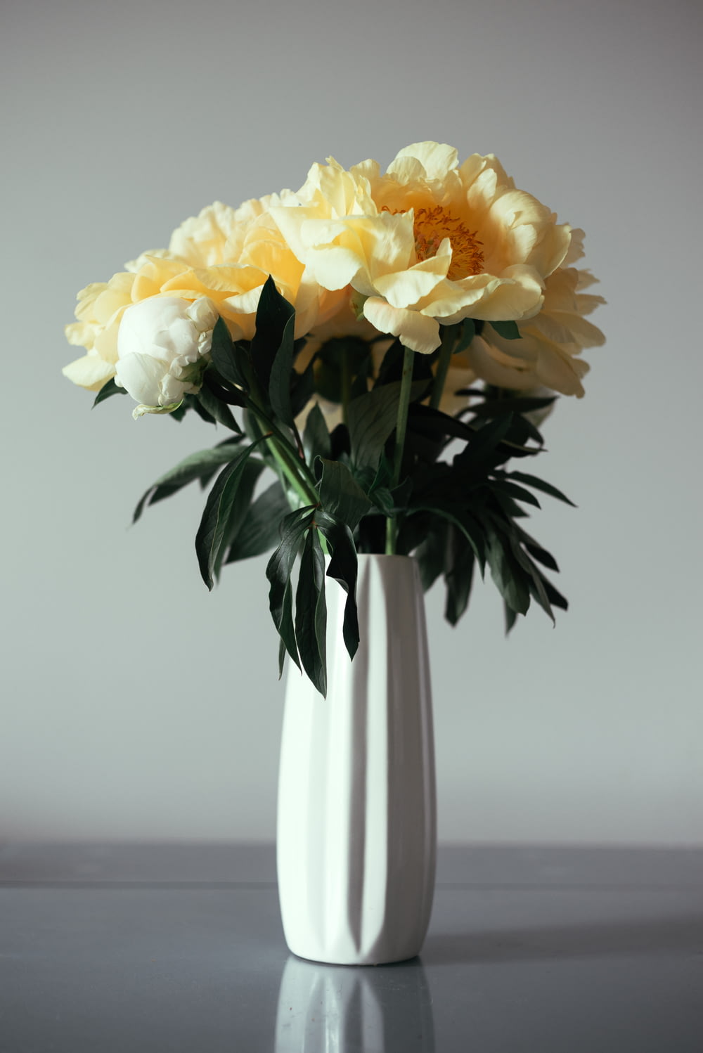 a white vase filled with yellow and white flowers