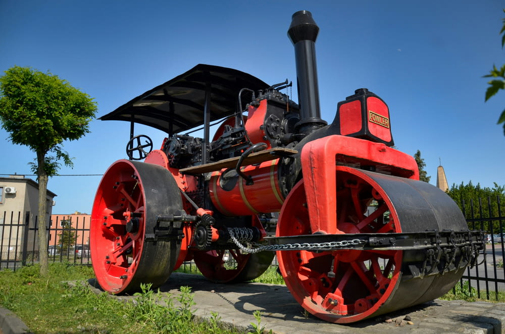 a red and black steam engine sitting on top of a sidewalk