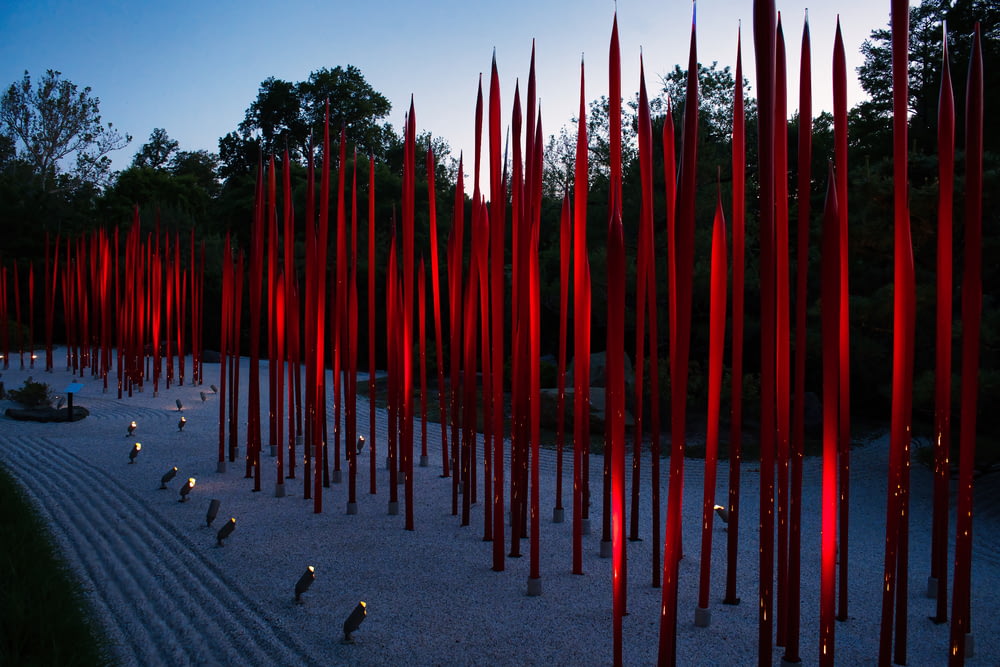 a large group of red poles in the middle of a park