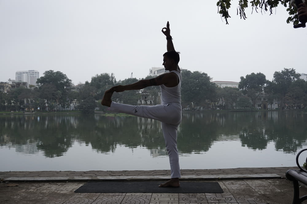 a person doing a yoga pose in front of a body of water