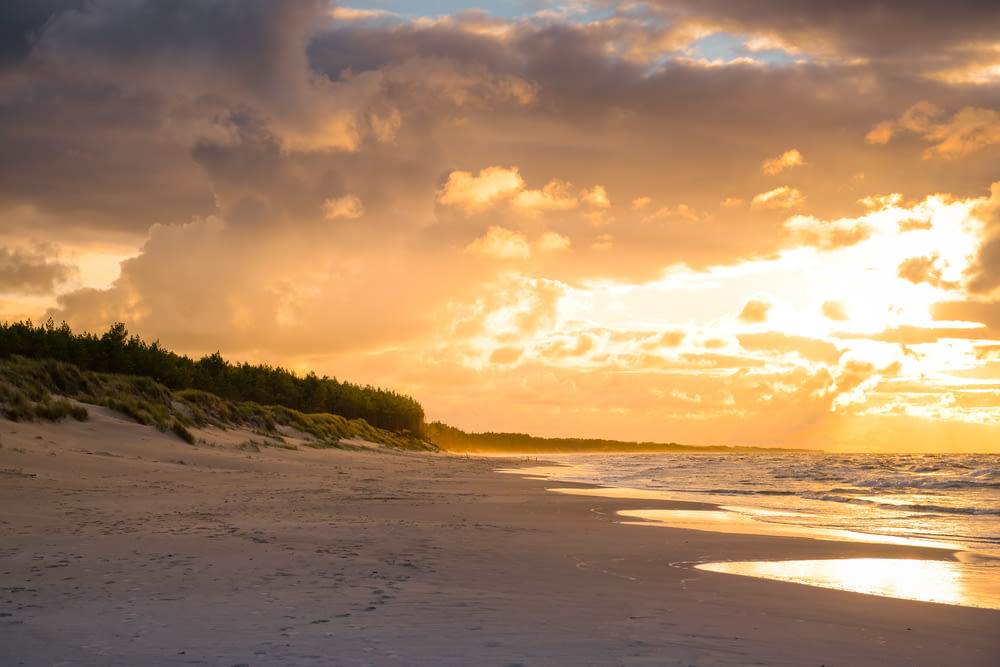 Il sole sta tramontando sulla spiaggia con impronte nella sabbia