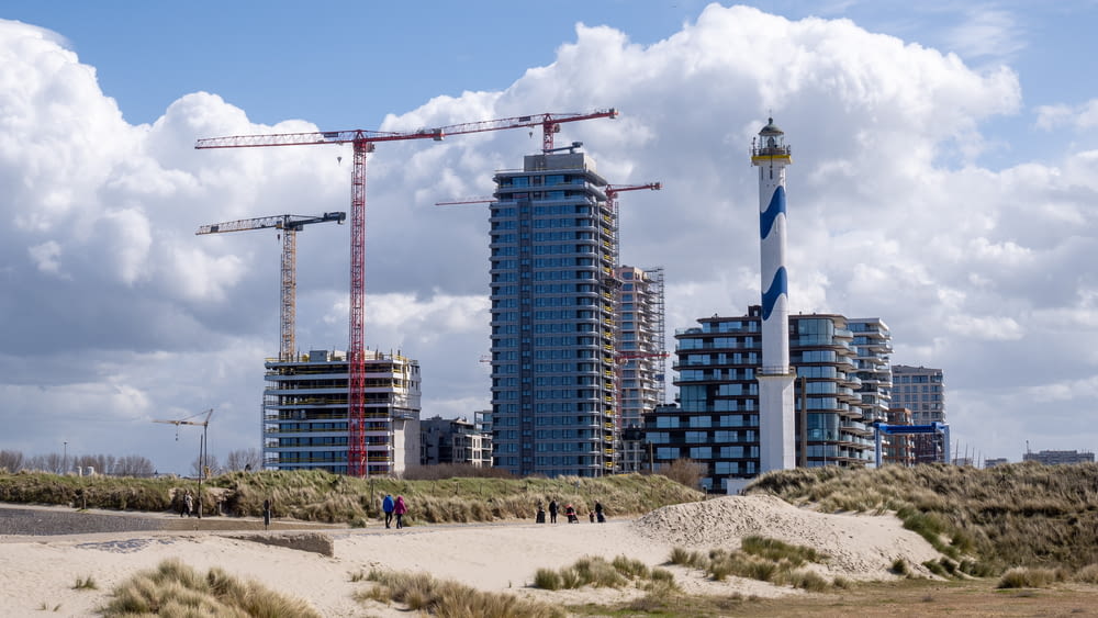 a group of people walking on a beach next to tall buildings