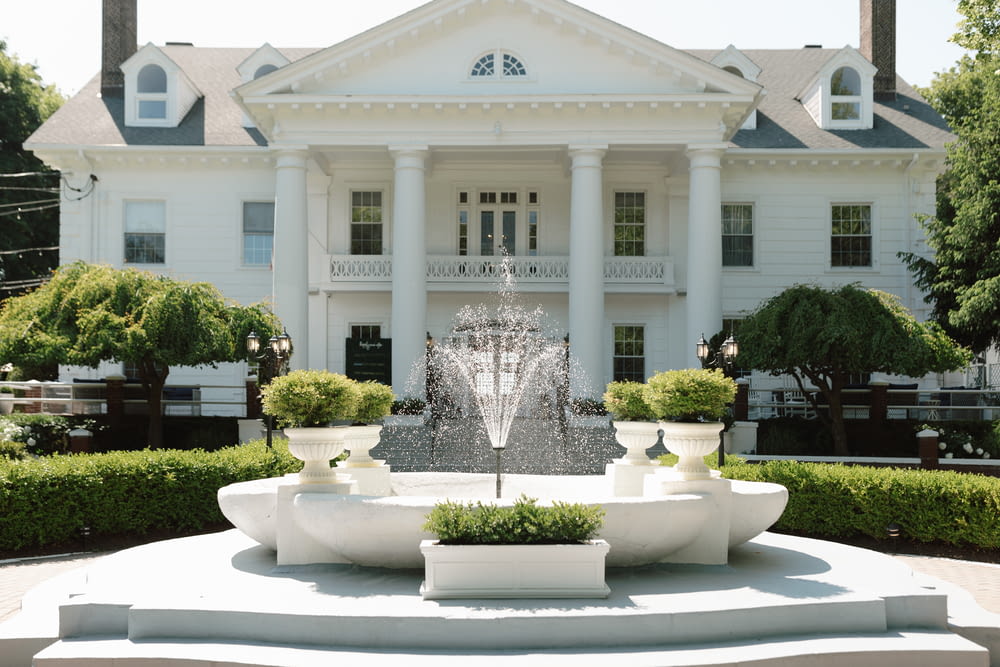 a large white house with a fountain in front of it