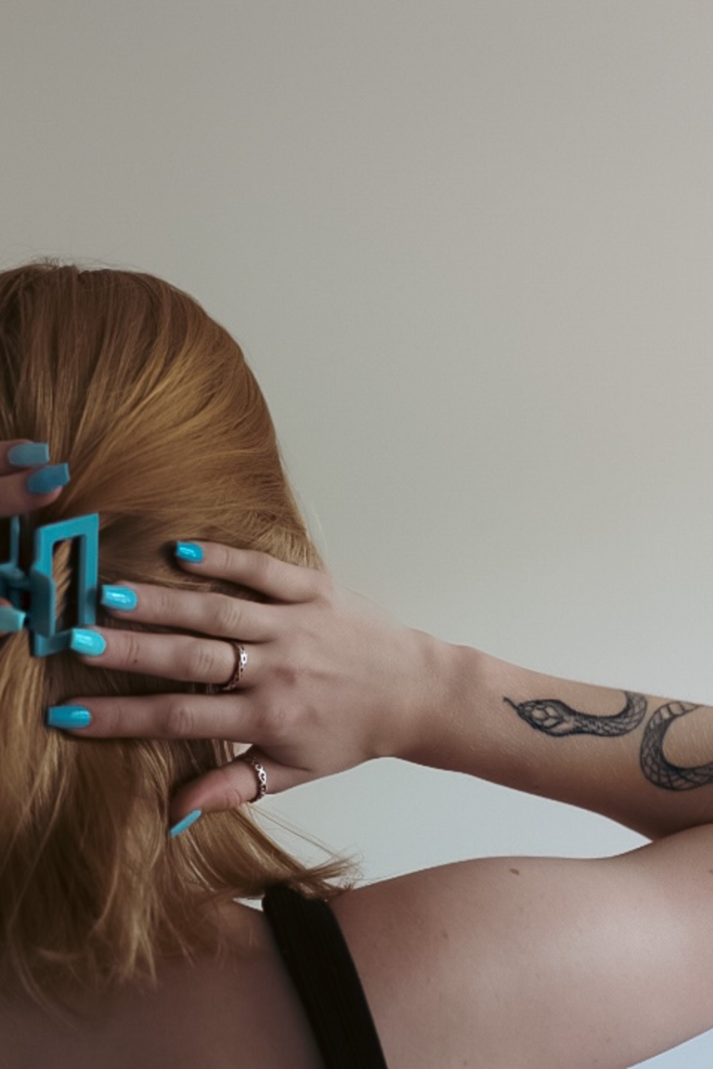 a woman with blue nail polish holding her hair