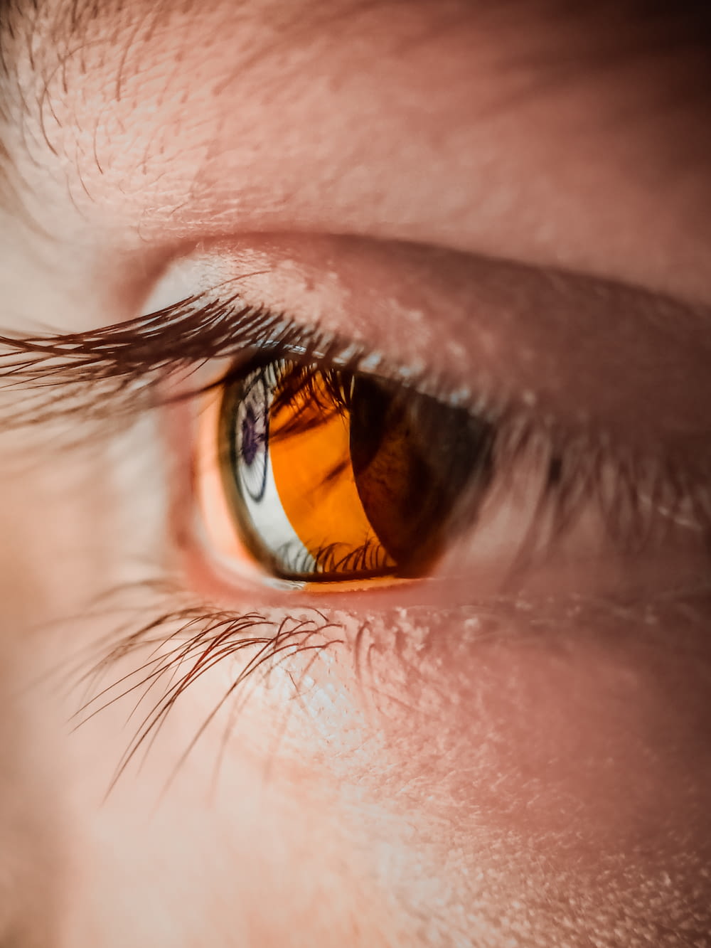 a close up of a person's eye with an orange iris