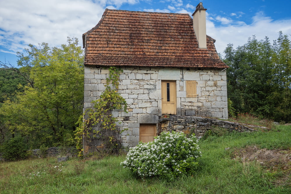 an old stone house with a red roof