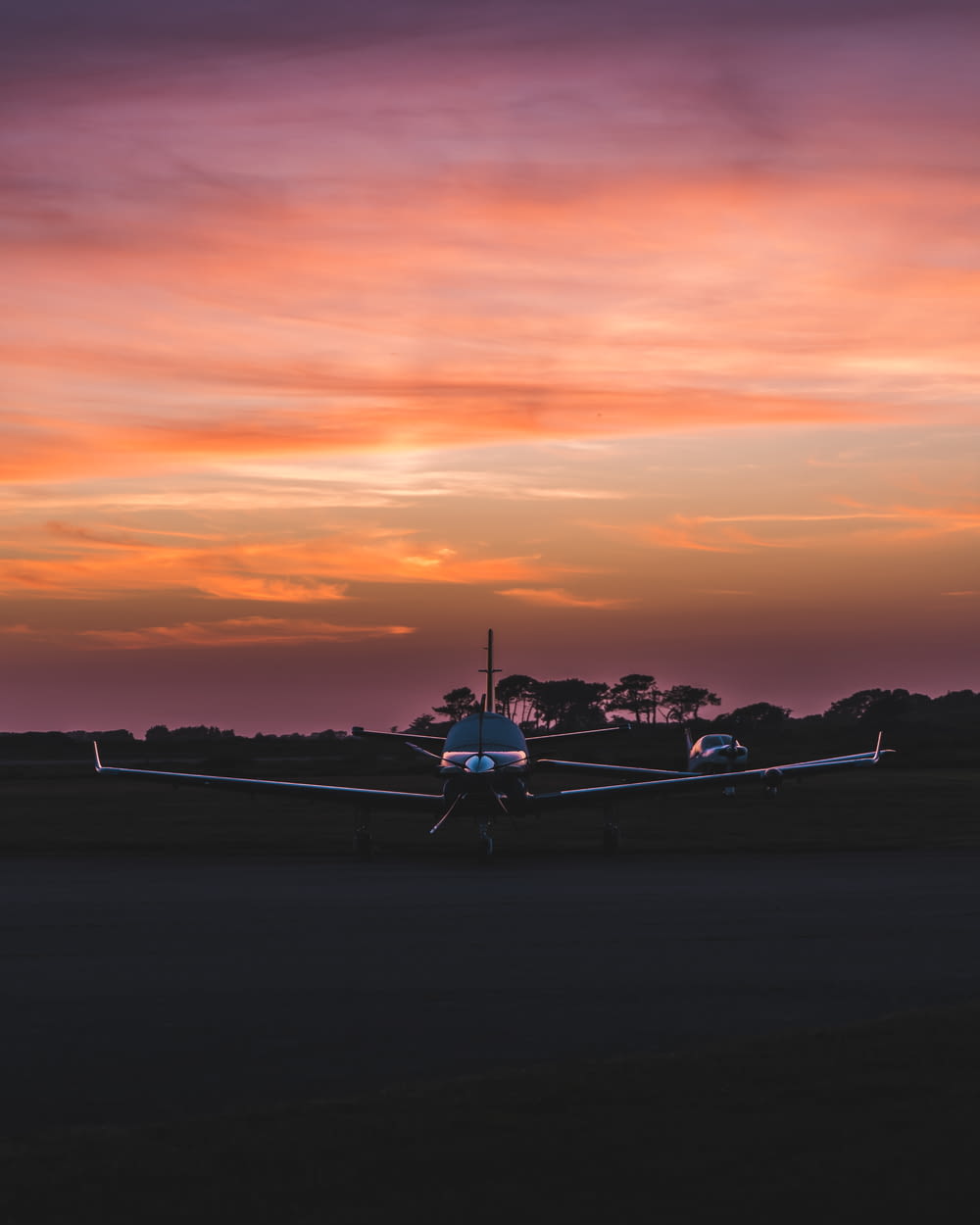 a plane is sitting on the runway at sunset
