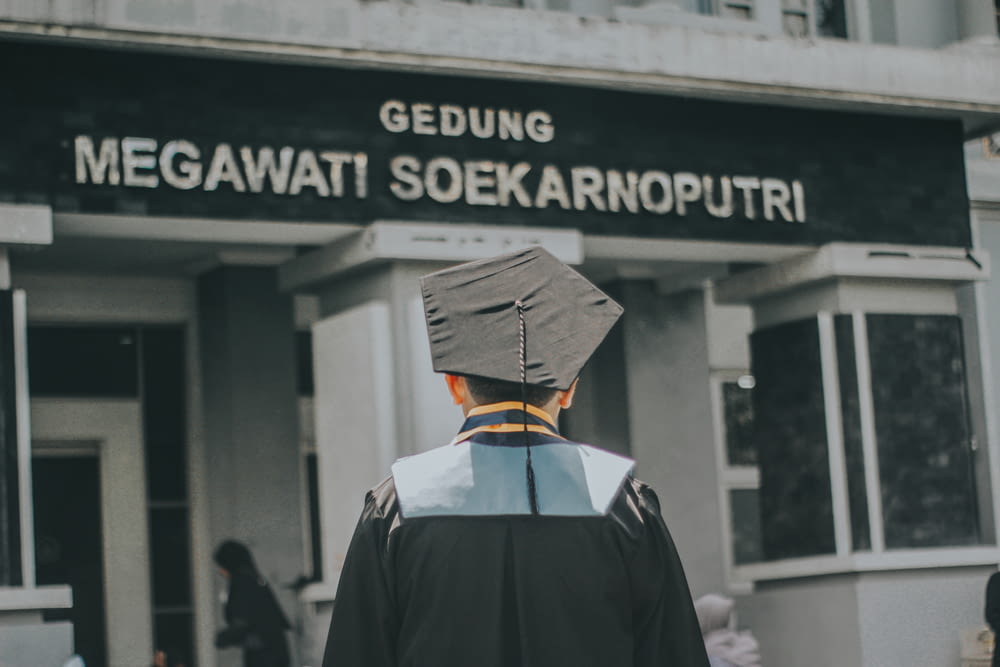 a man in a cap and gown walking towards a building