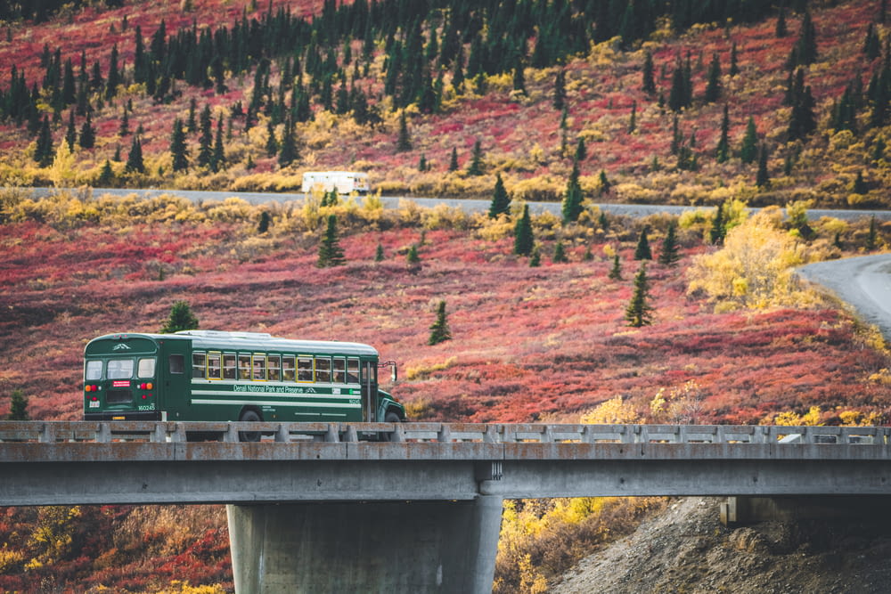 Un bus vert roulant sur un pont dans les montagnes