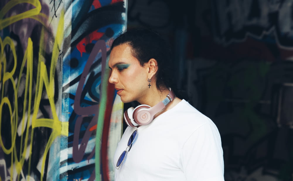그래피티로 뒤덮인 벽 앞에 서 있는 헤드폰을 쓴 여성