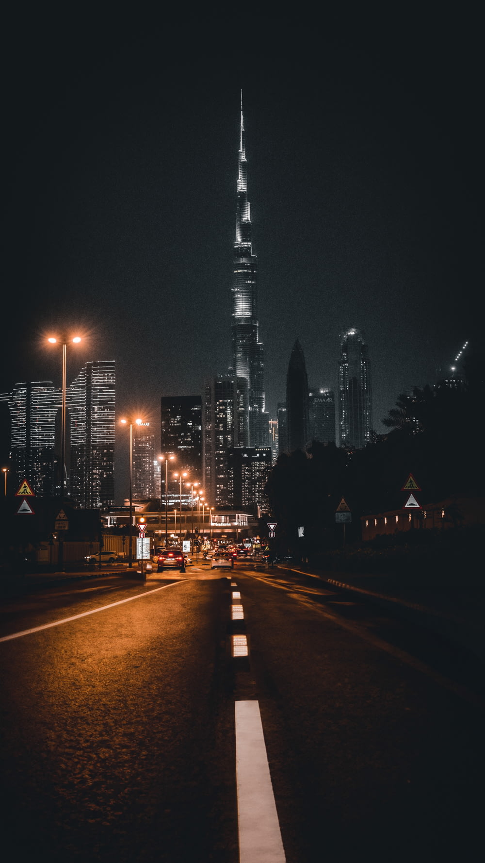 a city street at night with a very tall building in the background