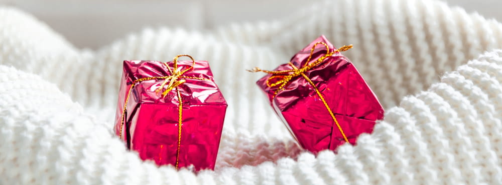 a pair of pink wrapped presents sitting on top of a white blanket