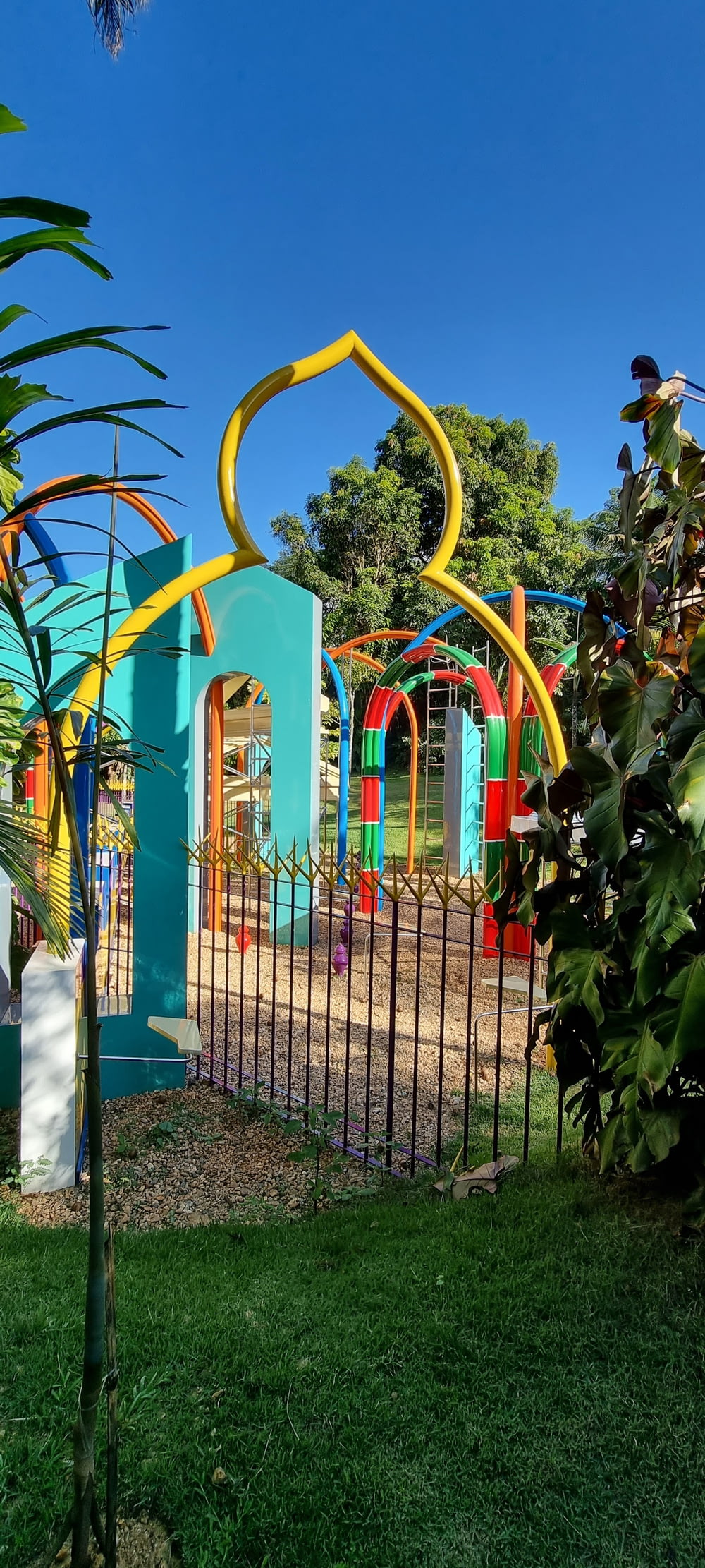a colorful playground in a park with a metal fence