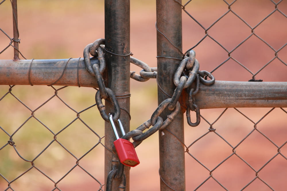 a red padlock attached to a chain link fence