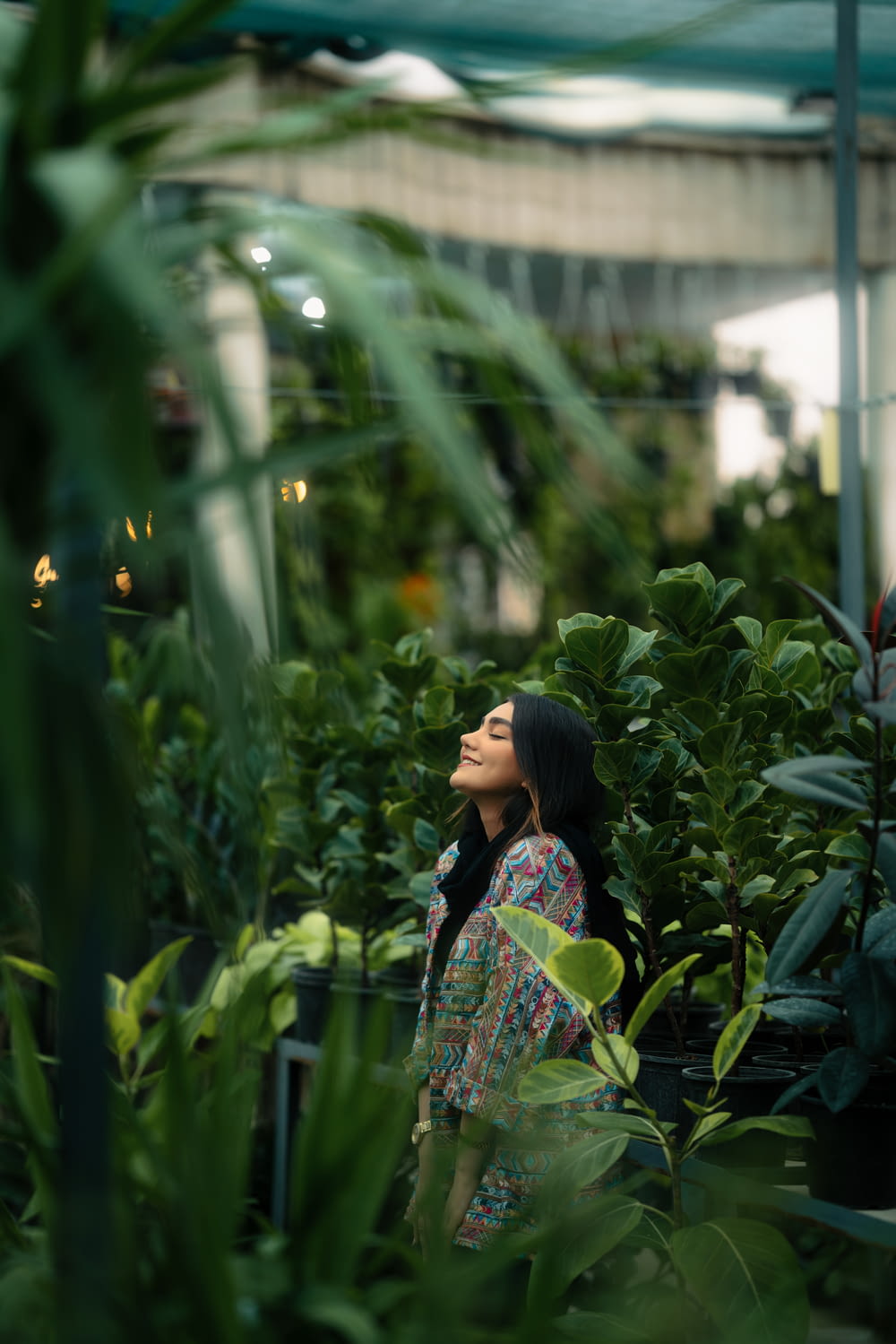 a woman standing in a greenhouse looking up into the sky