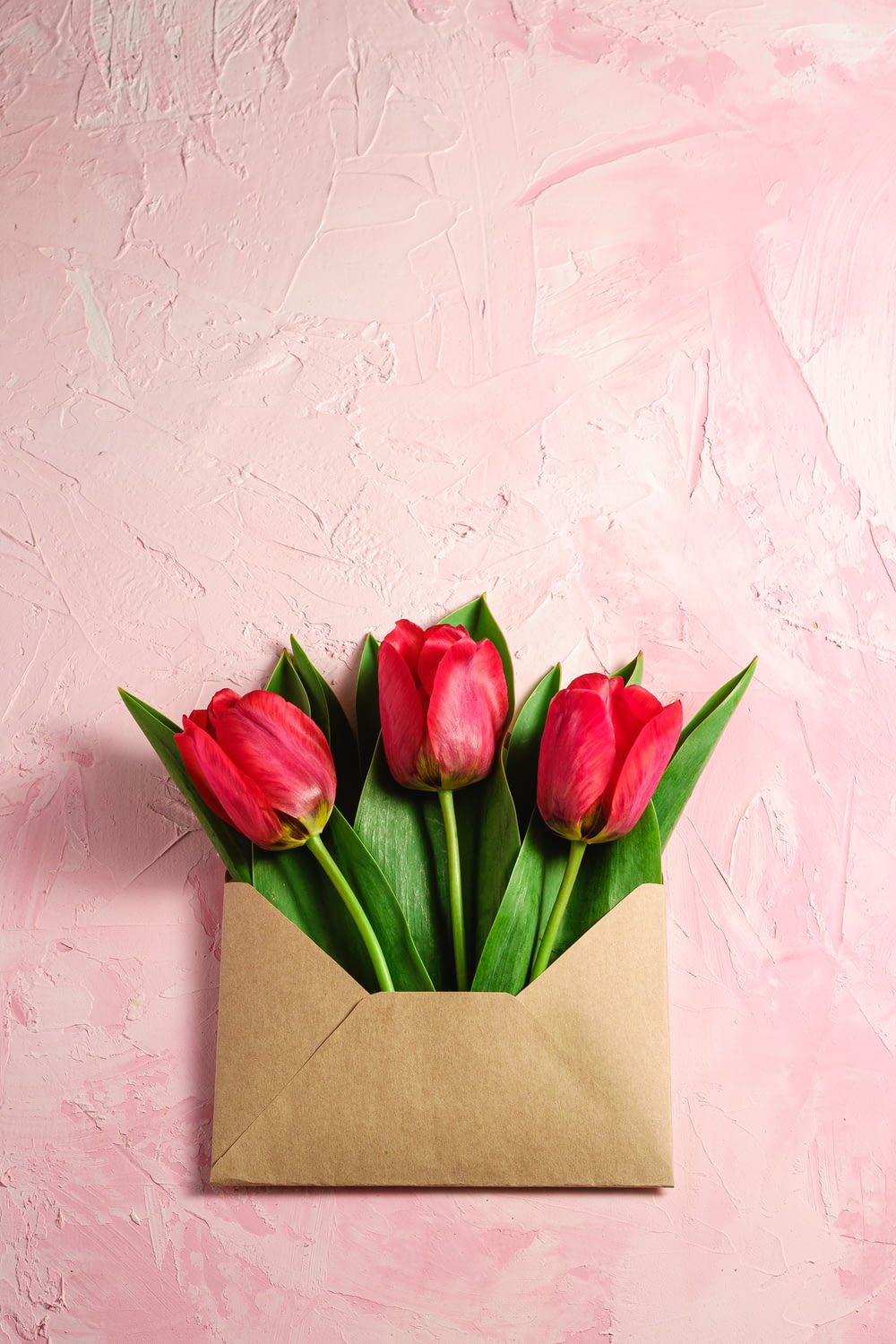 un ramo de tulipanes rojos en un sobre marrón