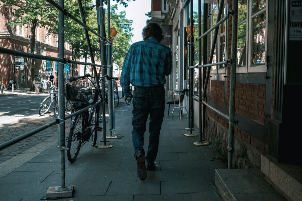 a man walking down a sidewalk next to a bike