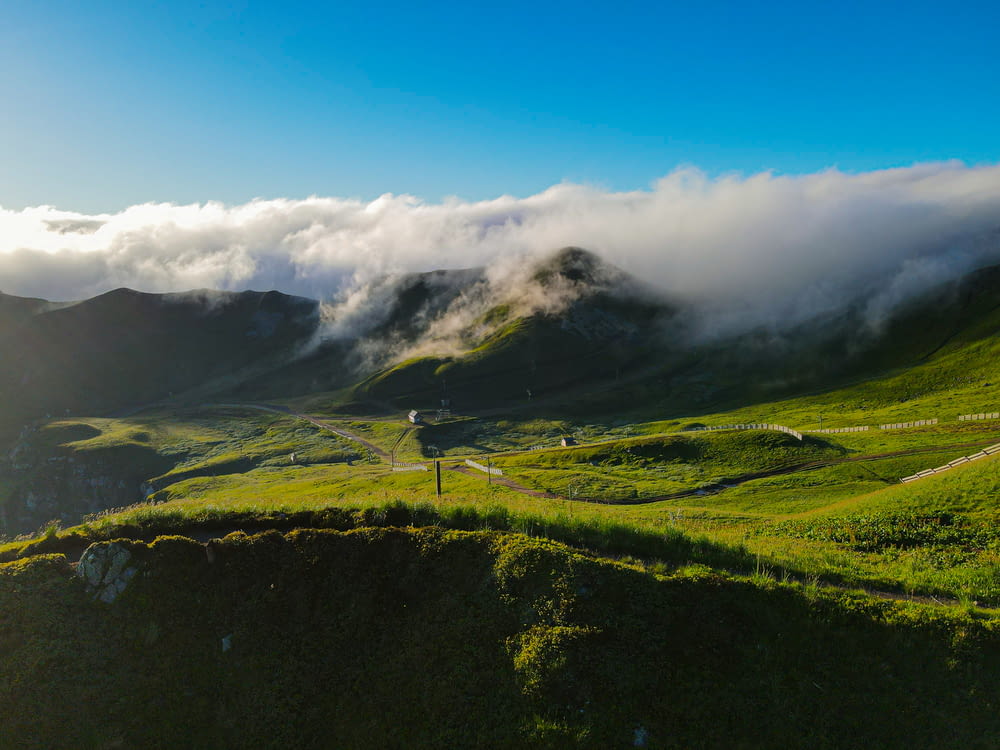 a lush green hillside covered in fog and clouds