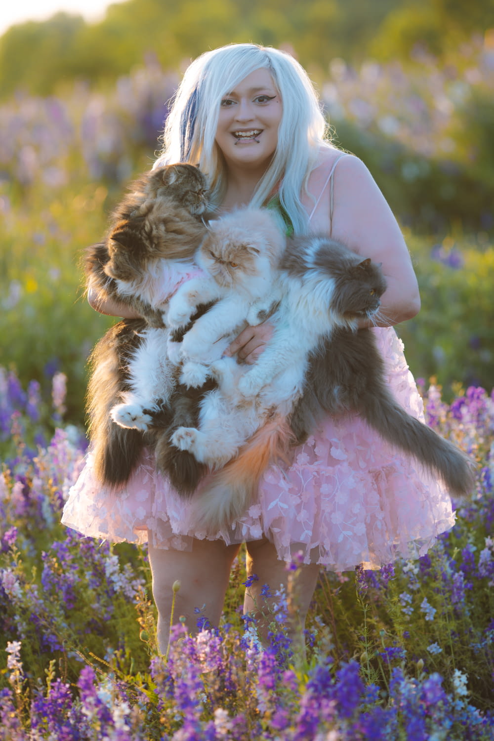 a woman holding a cat in a field of flowers
