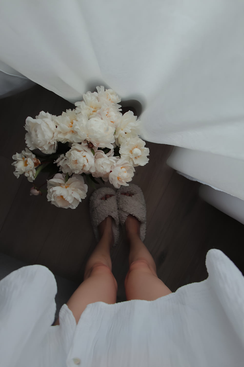 a bouquet of white flowers sitting on top of a person's feet