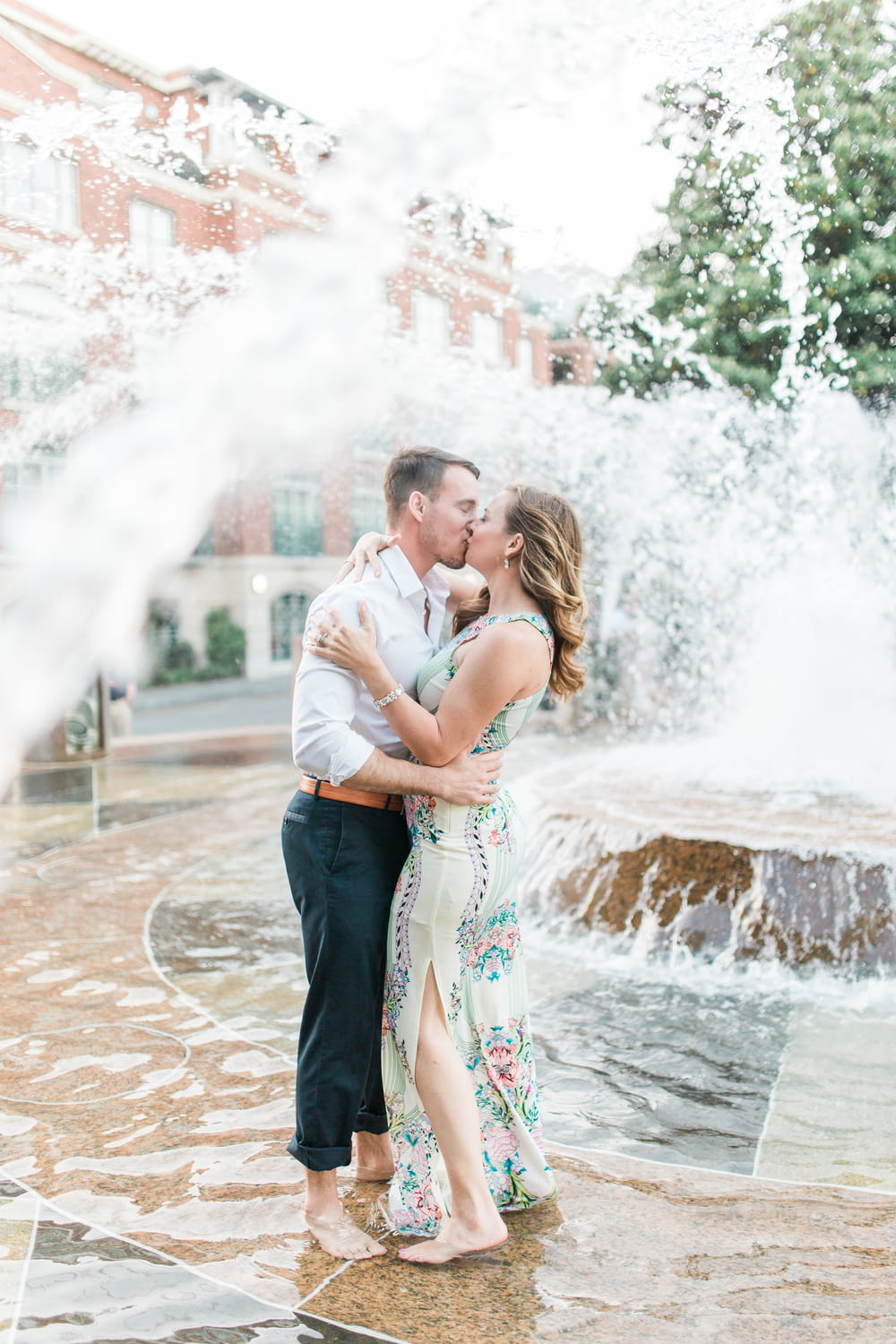 a man and woman kissing in front of a fountain