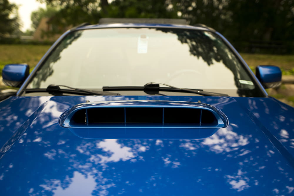 a close up of a blue car with trees in the background