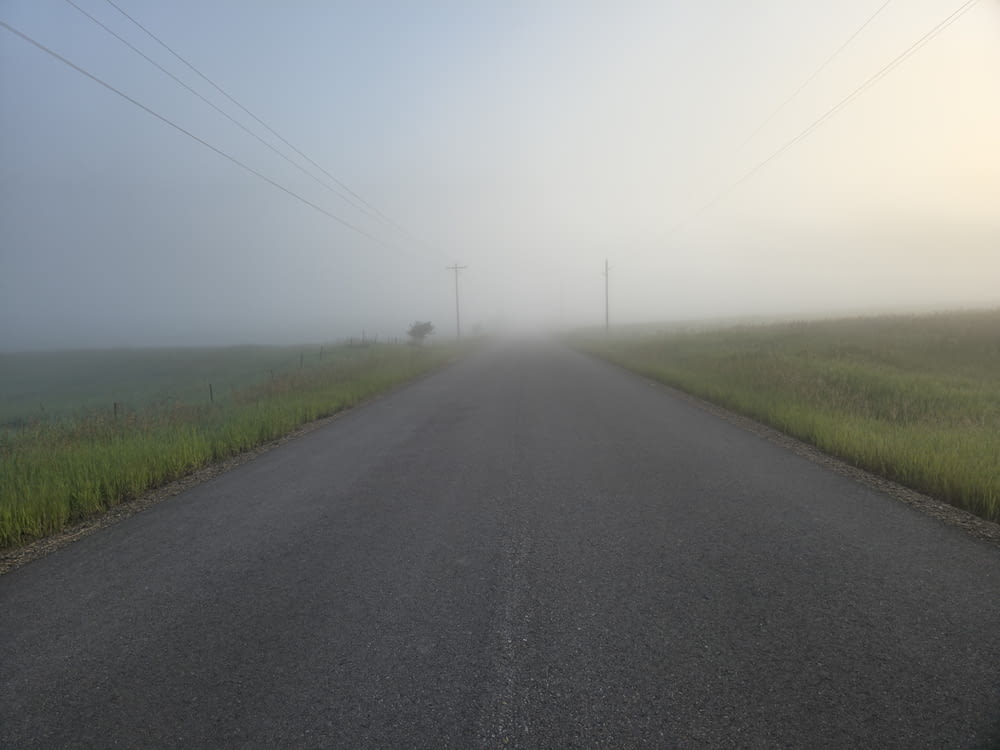 a foggy road with power lines in the distance