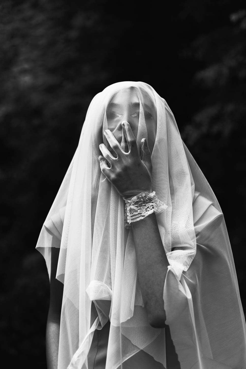 a woman wearing a veil and holding her hands to her face
